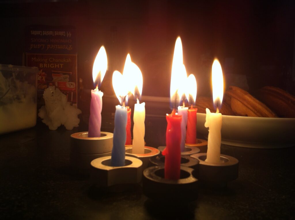 A collection of small candles all alight. Each candle is held within a small metal disk.